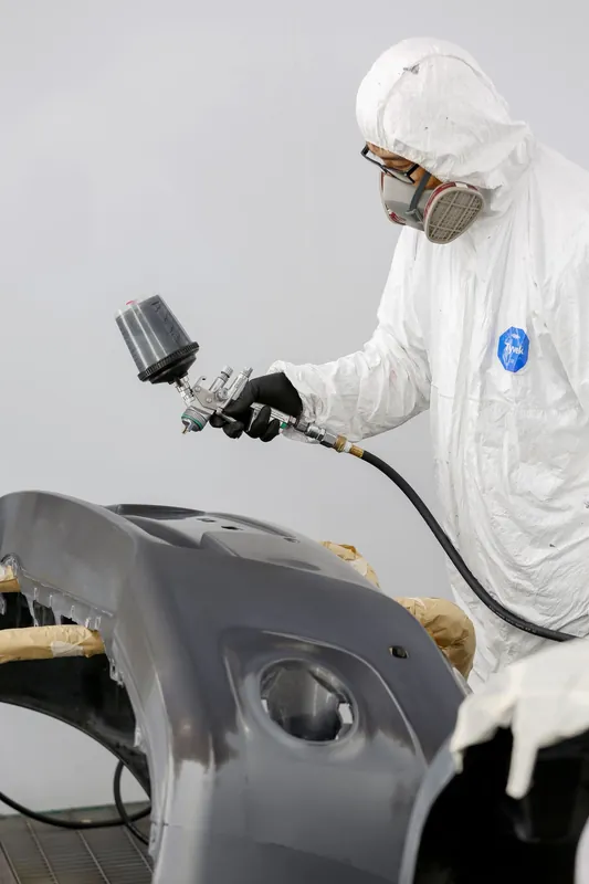 Painter spraying a panel in a booth